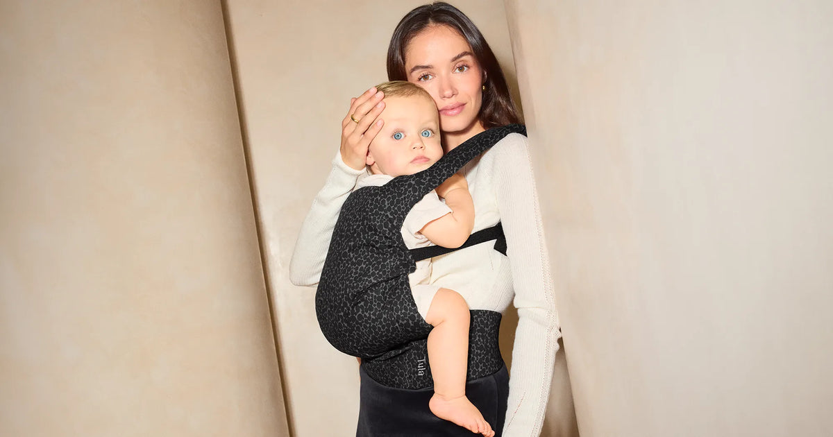 Woman carrying her baby in the Tula Explore Baby Carrier in Black Mirage Cotton