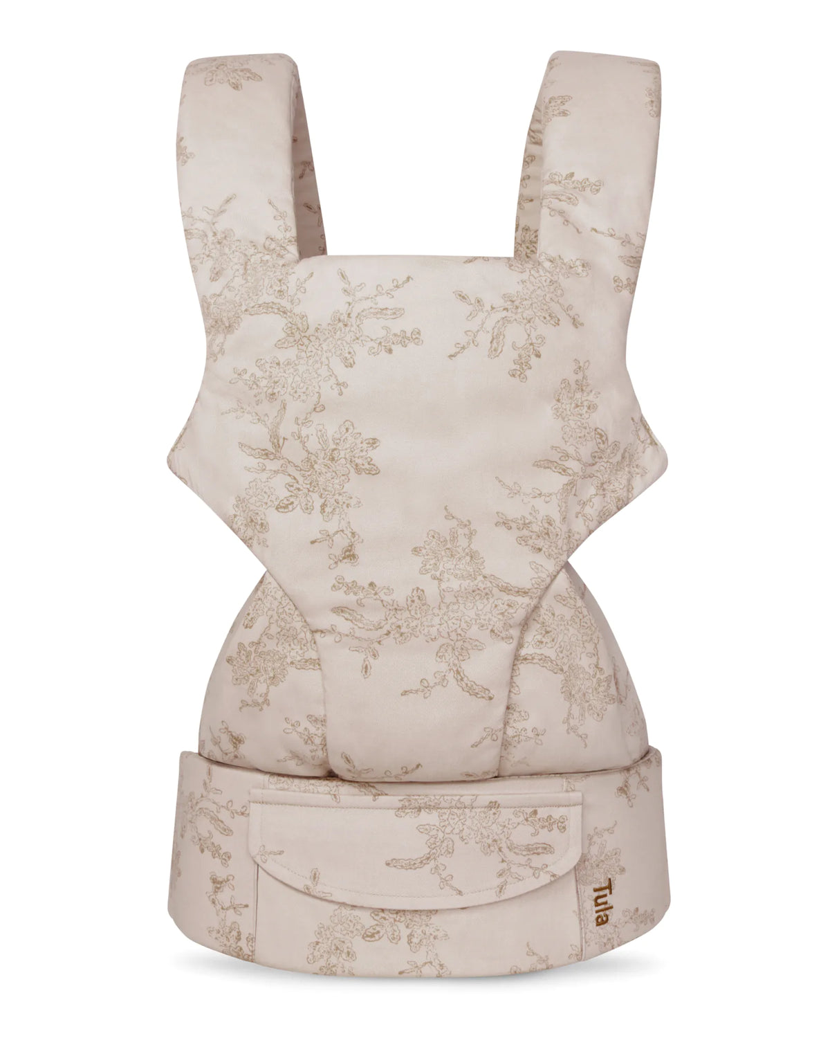 A cotton baby carrier in a light beige fabric with a delicate taupe floral toile pattern, featuring a front pouch and a small visible Tula brand label.