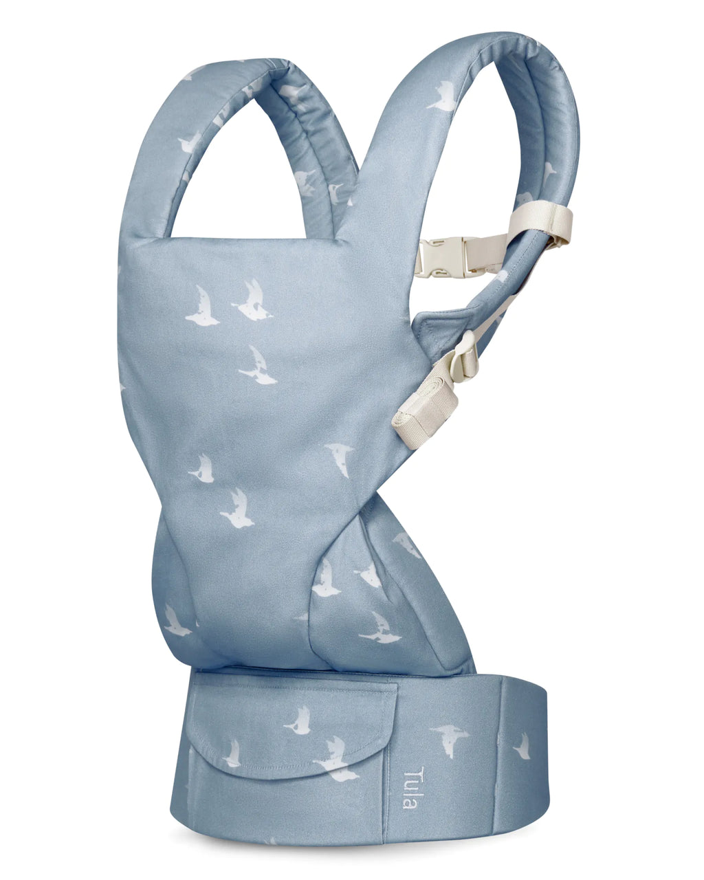 A light blue cotton baby carrier with a white bird pattern, shown on a plain white background. The brand name 'Tula' is visible on the front waist belt.