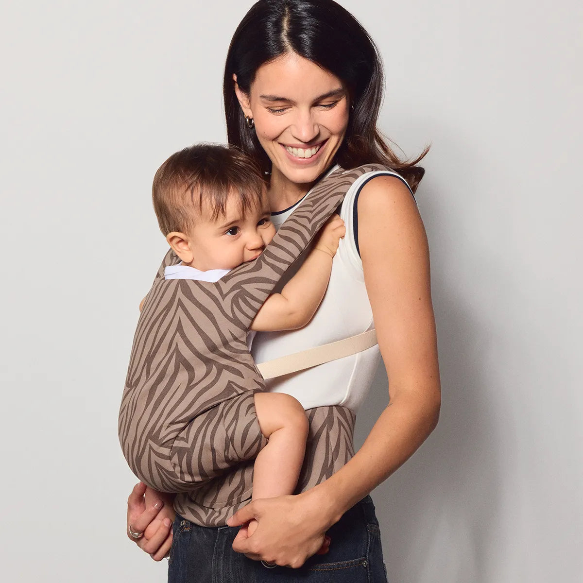 A woman wearing the tula explore baby carrier in Sahara Stripe.