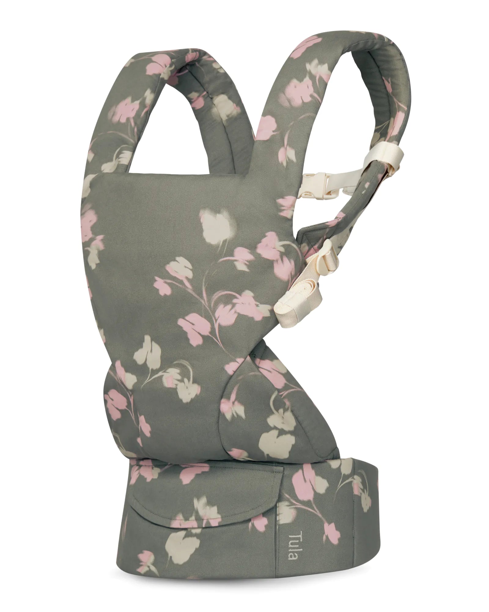 A cotton baby carrier in a muted gray-green fabric with a pink and white floral pattern, featuring cream-colored plastic buckle closures. The brand name 'Tuia' is visible on a small fabric tag on the bottom waist belt.