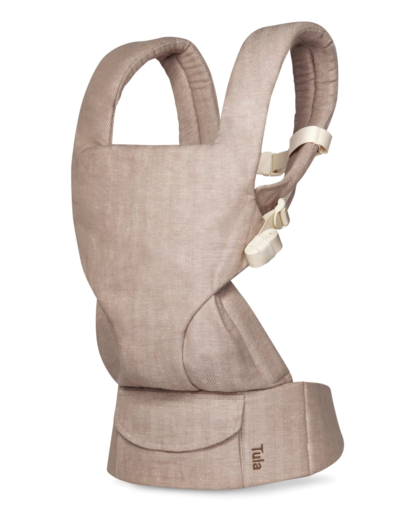 A Tula brand linen baby carrier in a light beige linen-like fabric, shown from a side profile view against a solid white background.