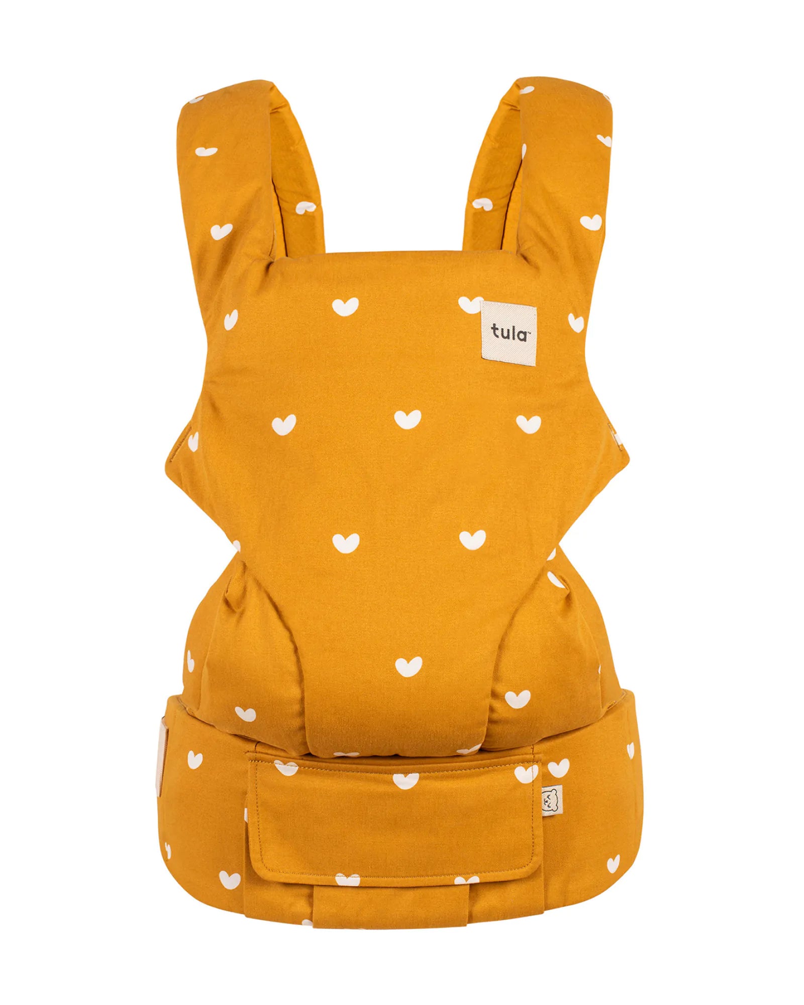 A mustard yellow baby carrier with a white heart pattern, featuring a small white brand label that reads 'tula'.