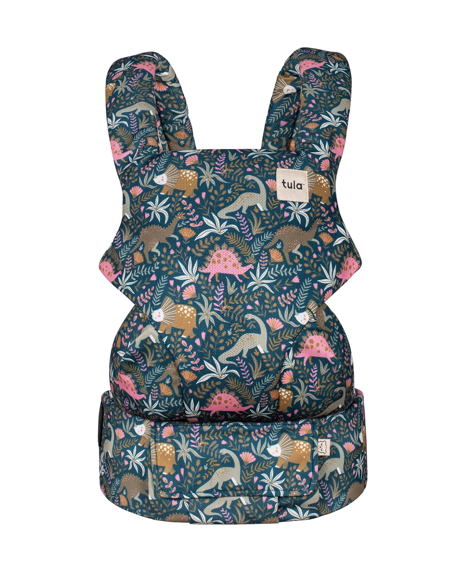 A baby carrier featuring a detailed all-over print of dinosaurs and botanical elements on a dark teal background. The brand name 'tula' is visible on a small white label on the upper right side.