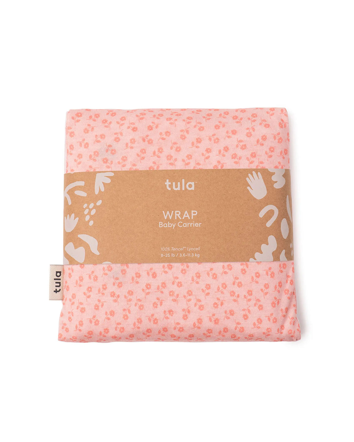 A folded Tula baby carrier wrap in a light pink color with a small orange floral pattern, wrapped in a brown kraft paper band with white text and illustrations, on a plain white background.