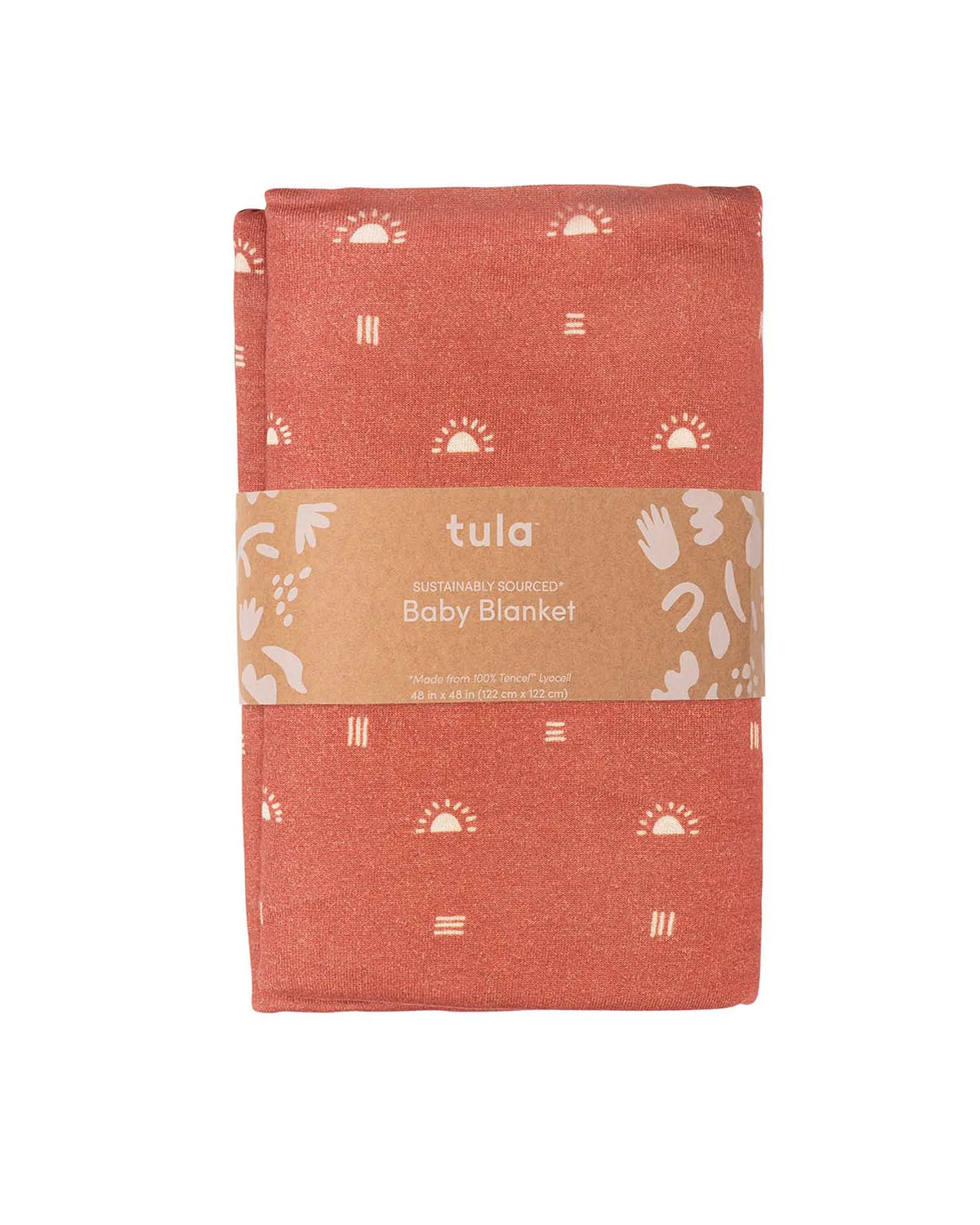 A folded Tula brand cotton baby blanket in a terracotta orange color, featuring a white sun and hand print pattern, wrapped in a brown paper band.