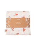 A folded Tula baby wrap with a light cream background and a coral-red and white mushroom pattern